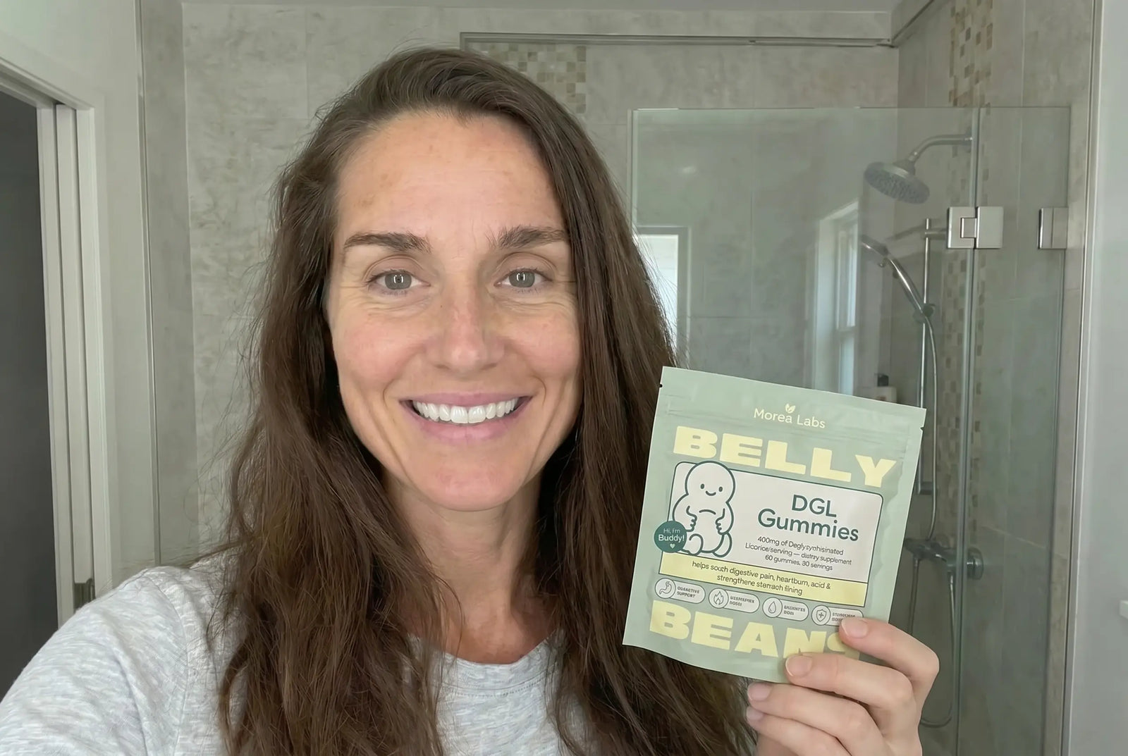 Woman holding Belly Beans DGL gummies in her kitchen